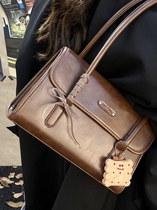 Sac à bandoulière vintage marron en cuir huilé avec un charmant pendentif biscuit