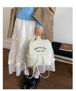 Détail d'un sac à dos en toile blanche avec fermeture à cordon et rabat imprimé