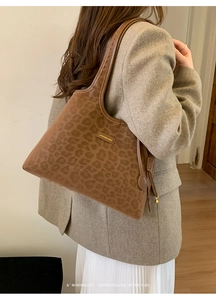 Détail du sac cabas vintage léopard avec étiquette cuir sur un manteau gris