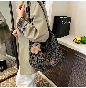 Detail of leopard print canvas bag with plush bear charm and leather logo tag