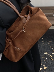 Large brown faux suede tote bag for women with leather handles in autumn park setting