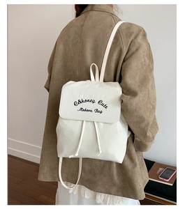 Détail d'un sac à dos blanc tendance avec broderie texte et fermeture par cordon de serrage