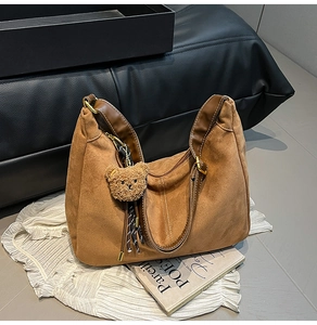 Detailed texture of brown suede hobo bag with teddy charm and gold metallic buckle