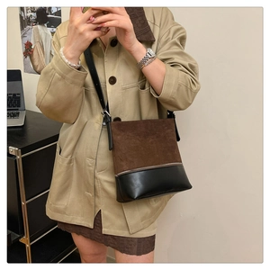 Detail view of contrast stitching leather bucket bag with suede texture and metal zipper