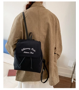 Vue détaillée d'un sac à dos en toile noire avec broderie blanche sur un mannequin femme