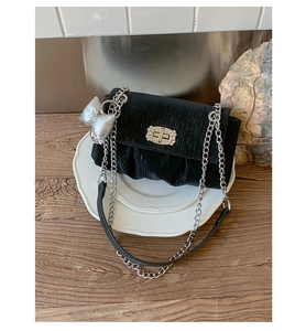 Detail of black velvet crossbody bag featuring silver chain and rhinestone square buckle