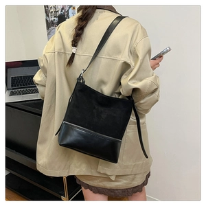 Detail of black patchwork tote bag showing suede and smooth leather texture on person