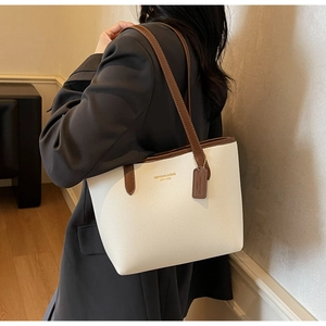 Close-up of litchi texture leather tote bag with contrast brown straps and logo