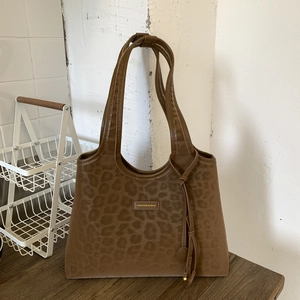 Gros plan du sac cabas à imprimé léopard avec pampille et plaque de mode gravée