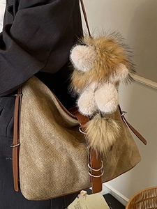 Brown woven tote bag with large plush lion charm shown as a stylish shoulder bag