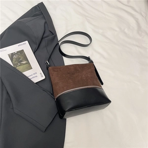 Detail view of two-tone bucket bag with brown suede and black smooth leather finish