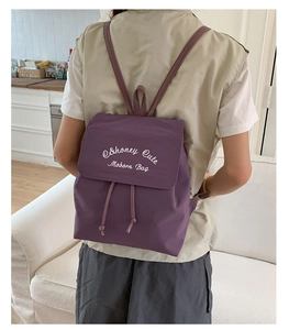 Détail du sac à dos en nylon violet avec fermeture à rabat, cordon et lettrage élégant