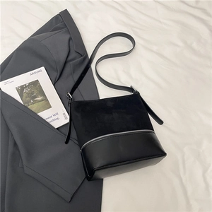 Detailed view of black patchwork leather bucket bag on stylish magazine background