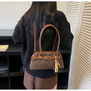 Detail of vintage leopard print shoulder bag with gold buckle and beaded pendant accessory
