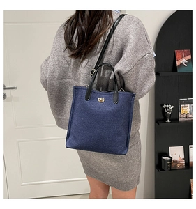Détail du sac cabas en jean bleu avec poignées en cuir noir et fermoir métallique doré