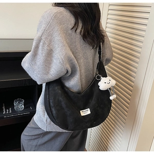 Detail of black suede crescent bag featuring Mulaidi label and plush cloud charm