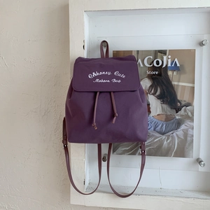 Détail du sac à dos en toile violette avec broderie blanche et fermeture à cordon
