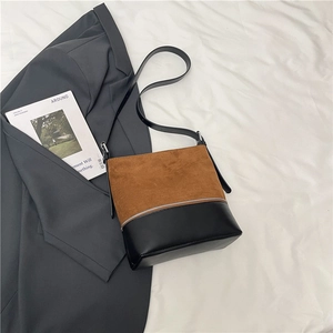 Detail showing the spliced leather texture and metal zipper design on a shoulder bag