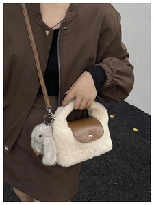 Detail of cream plush handbag with brown leather flap and cute rabbit charm accessory
