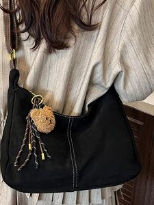 Minimalist large hobo bag in black suede texture with contrast stitching and bear charm