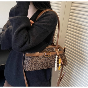 Detail of leopard print shoulder bag with brown leather trim and beaded charm accessory