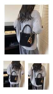 Detail view of large black suede bucket bag featuring colorful wooden bead charm on shoulder strap