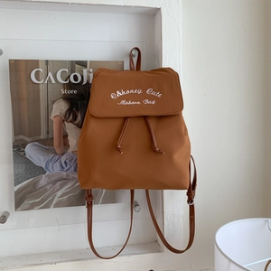 Vue détaillée du sac à dos en toile marron caramel avec cordon et broderie de marque