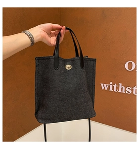 Détail du sac cabas en denim avec fermoir tournant doré et poignée en cuir élégante
