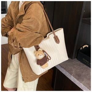 Detail of white woven tote bag texture with brown leather straps and cute bear charm