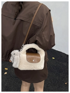 Detail of plush cream faux fur bag with brown leather flap and a rabbit charm