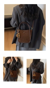 Detail of dark brown suede bucket bag with colorful wooden bead charm and handle