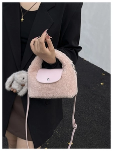 Detailed shot of pink plush faux fur handbag with leather flap and rabbit keychain charm