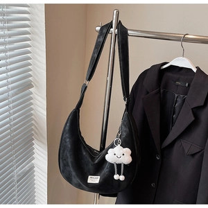 Detail of black crescent hobo bag with adjustable strap and plush cloud charm