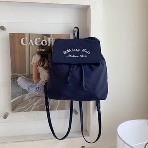 Gros plan du sac à dos en nylon bleu marine avec broderie blanche et bretelles réglables
