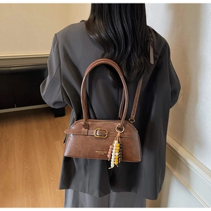 Detailed view of brown vintage underarm bag with beaded tassel and metal buckle