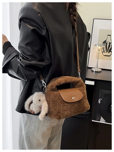 Detail view of brown plush tassel bag with lamb wool texture and cute bunny charm accessory
