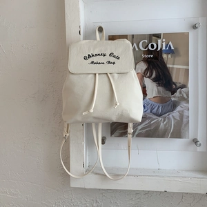 Vue détaillée de la texture en toile crème et de la broderie sur ce sac à dos élégant