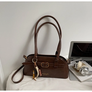 Detailed close-up of dark brown vintage leather shoulder bag with gold hardware and brand logo