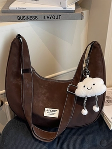 Large dark brown suede crescent bag with visible white stitching and cloud pendant