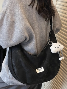 Black crescent shoulder bag with cloud plush charm and letter patch on grey knit sweater