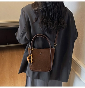 Detail view of the coffee brown suede hobo bag with vintage wooden bead charm and snap button