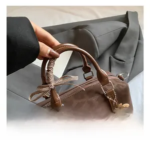 Detail of a brown Boston bag handle with checkered silk scarf and plush toast charm