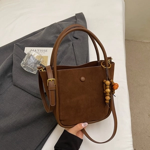Detailed close-up of a brown suede bucket bag featuring high-quality leather and wooden bead
