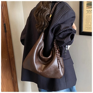 Detail of dark brown leather hobo bag with braided charm and vintage knotted shoulder strap