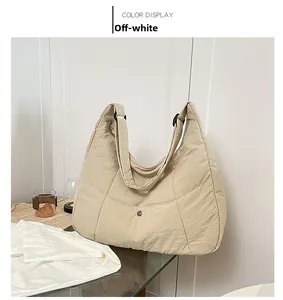 Detail view of the off-white quilted shoulder bag with snap button pocket and wide strap