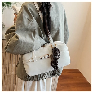 Detail of white minimalist shoulder bag with vintage metallic buckle and brown charm