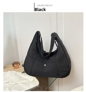 Detail of black quilted nylon tote bag with adjustable shoulder strap and snap closure