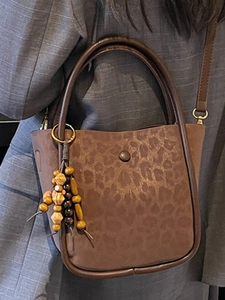 Brown leopard print suede bucket bag with wooden bead charm and long shoulder strap