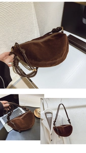 Detail of dark brown suede crescent bag with knot strap and zip closure on white background
