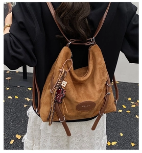 Caramel faux suede backpack with a cute bear pendant shown on an autumn street